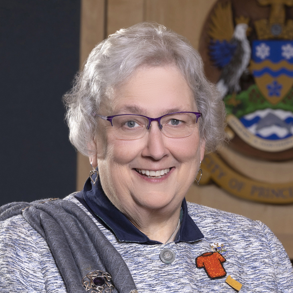 Headshot of Councillor Susan Scott in council chambers, with City of Prince George crest partially visible in background.